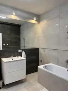 a bathroom with a bath tub and a sink and a bath tub at Apartament Magnoliowy in Owińska