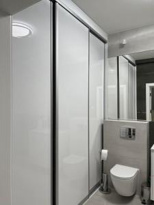 a bathroom with a toilet and a glass shower at Apartament Magnoliowy in Owińska
