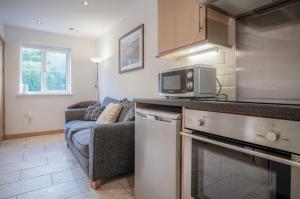 a kitchen with a microwave and a couch in a room at Three Cliffs Cottage - 2 Bedroom - Parkmill in Parkmill