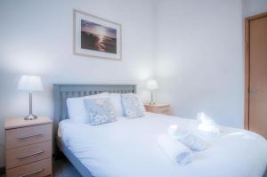 a bedroom with a white bed with towels on it at Three Cliffs Cottage - 2 Bedroom - Parkmill in Parkmill