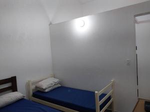 1 dormitorio con 2 camas y una luz en la pared en Casa a 5 minutos a pé da Praia da Enseada! en Bertioga