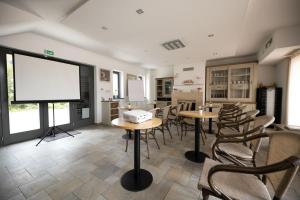 a room with tables and chairs and a large screen at Flamingó Panzió és Borház in Etyek