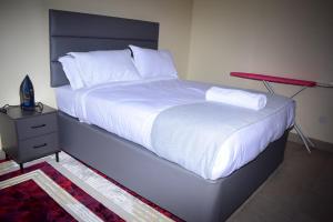 ein großes Bett mit weißer Bettwäsche und Kissen in der Unterkunft San Haven in Kisumu