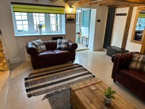 een woonkamer met 2 leren banken en een tapijt bij Stunning 4 Bedroom Cottage-Sleeps 8-Free Parking in Gloucester