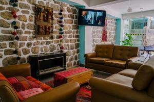 una sala de estar con sofás y una pared de piedra. en Magar Hostel Bar, en Cusco