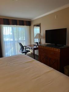 a hotel room with a bed and a desk with a television at Hotel Xola in Moreno Valley