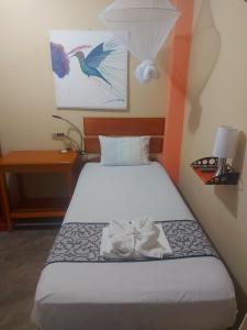 a bed in a small room with a white bedsheet at Amazon House Hostel in Iquitos