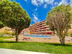 a building with a swimming pool and two trees at Kpaco Apartment in Puerto de Santiago