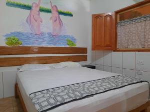 a bedroom with a bed and a painting of three flamingos at Amazon House Hostel in Iquitos