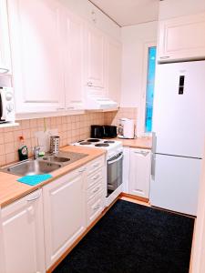 a kitchen with white cabinets and a white refrigerator at Aurora City Apartment in Rovaniemi