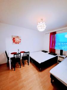 ロヴァニエミにあるAurora City Apartmentのベッド2台、テーブル、椅子が備わる客室です。