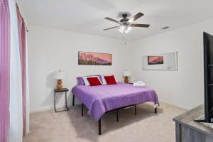 a bedroom with a purple bed with a ceiling fan at Chic Townhouse by LSU in Baton Rouge