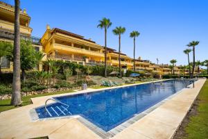 una piscina frente a un edificio con palmeras en Sierra Blanca, en Marbella