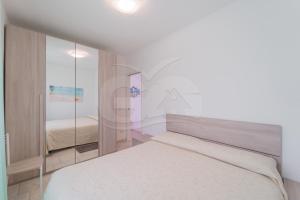 a white bedroom with a bed and a mirror at Albero del Pepe 2 - Goelba in Marina di Campo