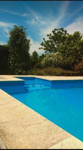 ein blauer Pool mit Bäumen im Hintergrund in der Unterkunft Casaquinta La Maju En La Reja! in La Reja