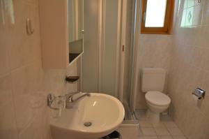 a white bathroom with a toilet and a sink at Immeuble Les Sérandes in Les Collons +17 photos
