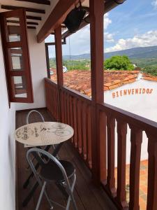 balcón con mesa, sillas y vistas en Rustico Hostel Barichara, en Barichara