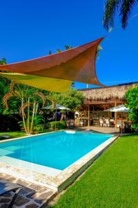 a swimming pool in front of a resort with an umbrella at Hotel Enjoy in Las Terrenas