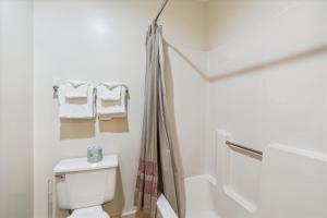a white bathroom with a toilet and towels at Cedarbrook Hotel Room w/2 Doubles 116 in Killington