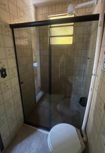 a bathroom with a toilet and a glass shower at Flat Maricá com ar-condicionado in Maricá