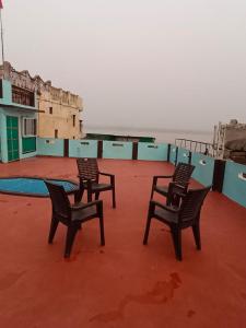 3 sedie sedute in cima a un edificio di Sankardev Guest House D24 35 a Varanasi