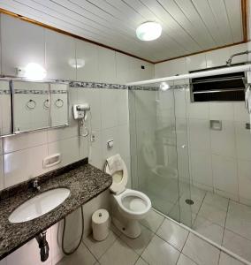 une salle de bain avec toilettes et douche en verre dans l'établissement Pousada Alpes da Serra Campos do Jordão, à Campos do Jordão