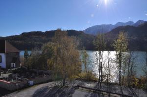 a view of a lake with a house and trees at Pension Rexha am Weißensee in Füssen