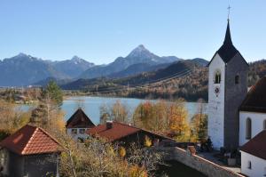 una chiesa con vista sul lago e sulle montagne di Pension Rexha am Weißensee a Füssen