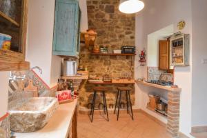 una cucina con pareti in pietra e bancone con sgabelli di La Torretta a Collelungo