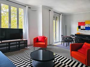 a living room with red chairs and a flat screen tv at L'Idrac, Appartements en Hyper centre in Toulouse