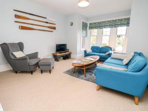a living room with blue couches and chairs and a tv at 5 The Nab House in Bembridge