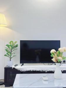 ein Wohnzimmer mit einem TV und einem Tisch mit Blumen in der Unterkunft Ninja's Sweet Home in Seremban