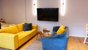 a living room with a yellow couch and two blue chairs at City Studio Kormoran in Bremerhaven