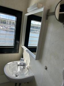 ein Bad mit einem Waschbecken und einem Spiegel in der Unterkunft Hausboot Floating 44 in Laboe - Boot 2 in Laboe