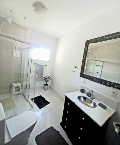 a white bathroom with a sink and a shower at Pousada Flor de Lis Homestay in Volta Redonda