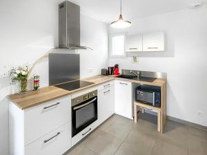 a kitchen with white cabinets and a stove top oven at L'Eclat de la Gironde in La Hourcade