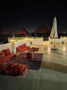 a patio with red pillows and a table and pyramids at Hur magic inn in Cairo