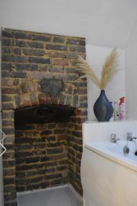 baño con chimenea de ladrillo y lavamanos en Gundulph house, en Rochester