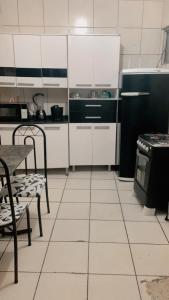 a kitchen with white cabinets and a black refrigerator at Apê da VAN in Garanhuns