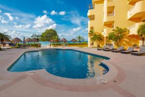 una piscina di fronte a un edificio con sedie di Playa Azul Cozumel a Cozumel Altre 85 foto