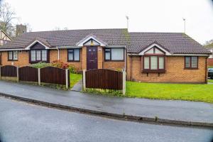 a brown brick house with a wooden fence at Charming 2-Bedroom in MANCHESTER in Manchester