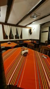 ein Esszimmer mit einem Tisch und einem orangenen Tischtuch in der Unterkunft The Old House Family Hotel in Welingrad