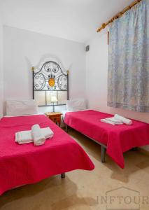 カルプにあるInftour Medici Apartamentoの赤いシーツとタオルが備わるドミトリールームのベッド2台分です。