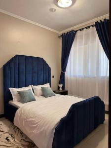 a large bed with a blue headboard in a bedroom at Cozy apartment in heart of Kampala in Kira