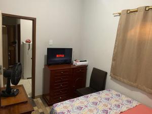 um quarto com uma cama e uma televisão numa cómoda em Apto Florescer - No Espaço Florescer em Campos dos Goytacazes