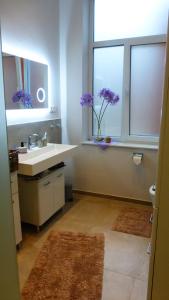 a bathroom with a sink and a window with purple flowers at City Studio Kormoran in Bremerhaven +27 photos