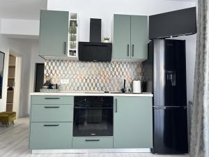 La cuisine est équipée de placards blancs et d'un réfrigérateur noir. dans l'établissement Eucalyptus Apartament, à Braşov