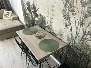 - une table avec deux assiettes vertes dans le salon dans l'établissement Eucalyptus Apartament, à Braşov