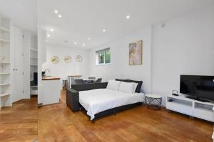 a white bedroom with a bed and a television at The Mews Apartment In Kensington in London