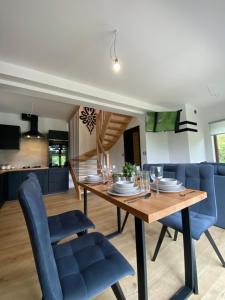 a dining room and kitchen with a wooden table and blue chairs at Zawoja Domki z Jacuzzi in Zawoja